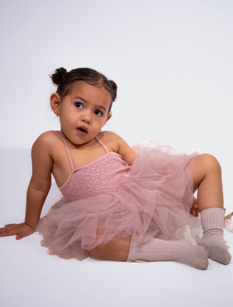 Niña sentada en el suelo del studio con tutú rosado